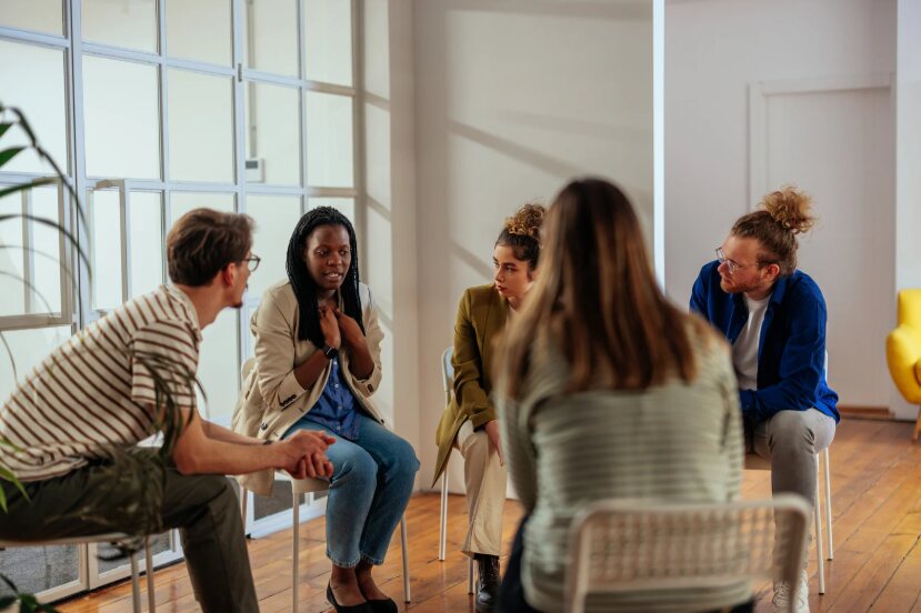 Un groupe de professionnels assis en cercle échange autour d'une situation présentée par l'une des participantes.
